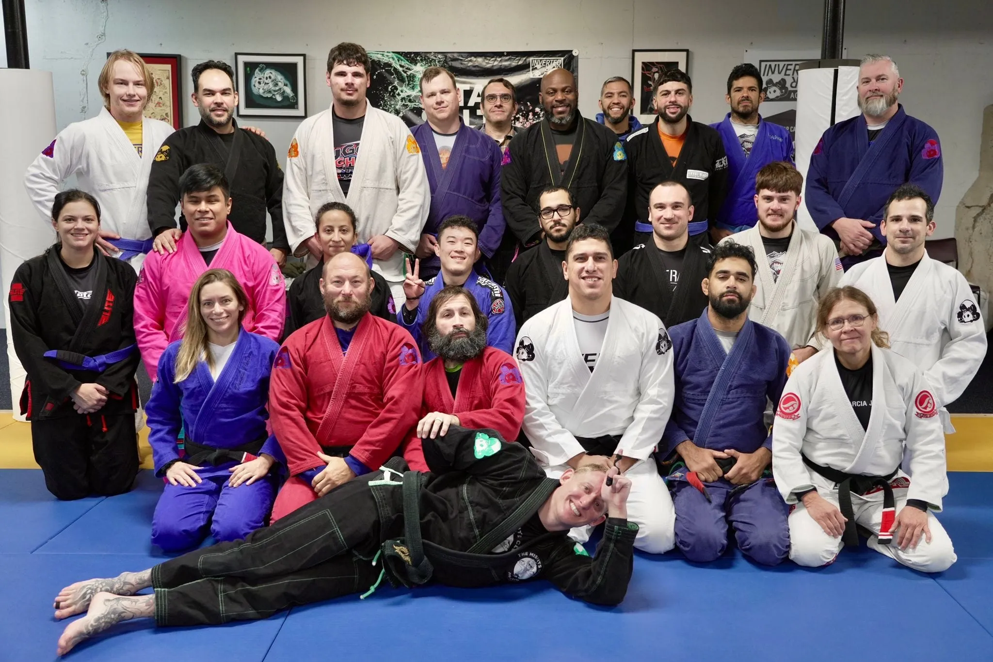 A jiu jitsu class in colorful gis poses for a playful group photo after training.