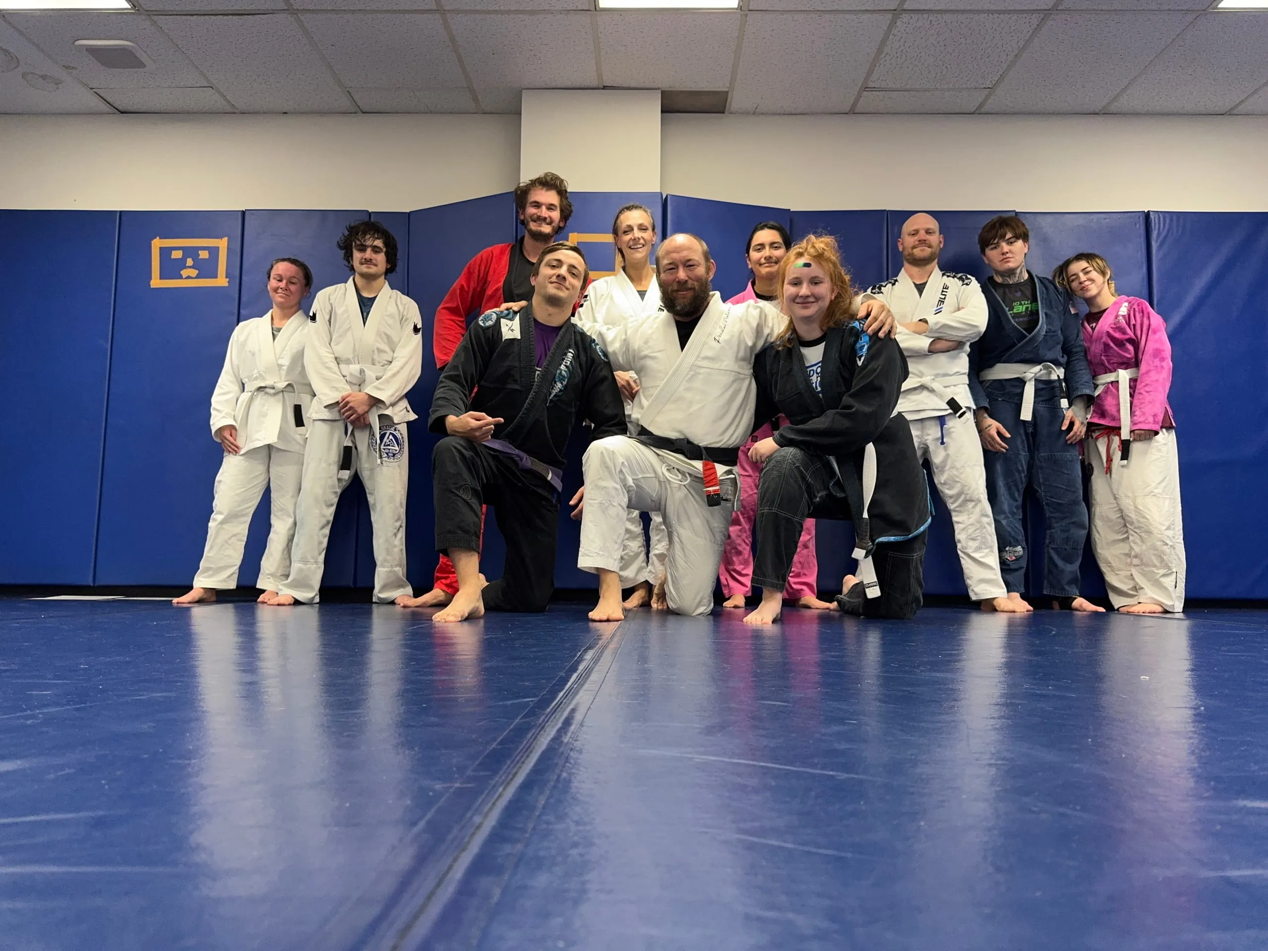 Eric Bydairk poses with his jiu jitsu class on the mats after a training session.