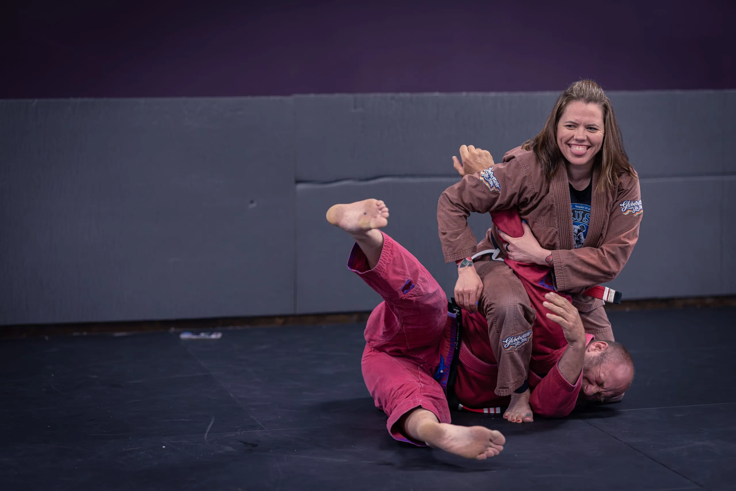 BJJ black belt Missy Baize smiles while pinning a training partner during a Brazilian Jiu Jitsu roll.